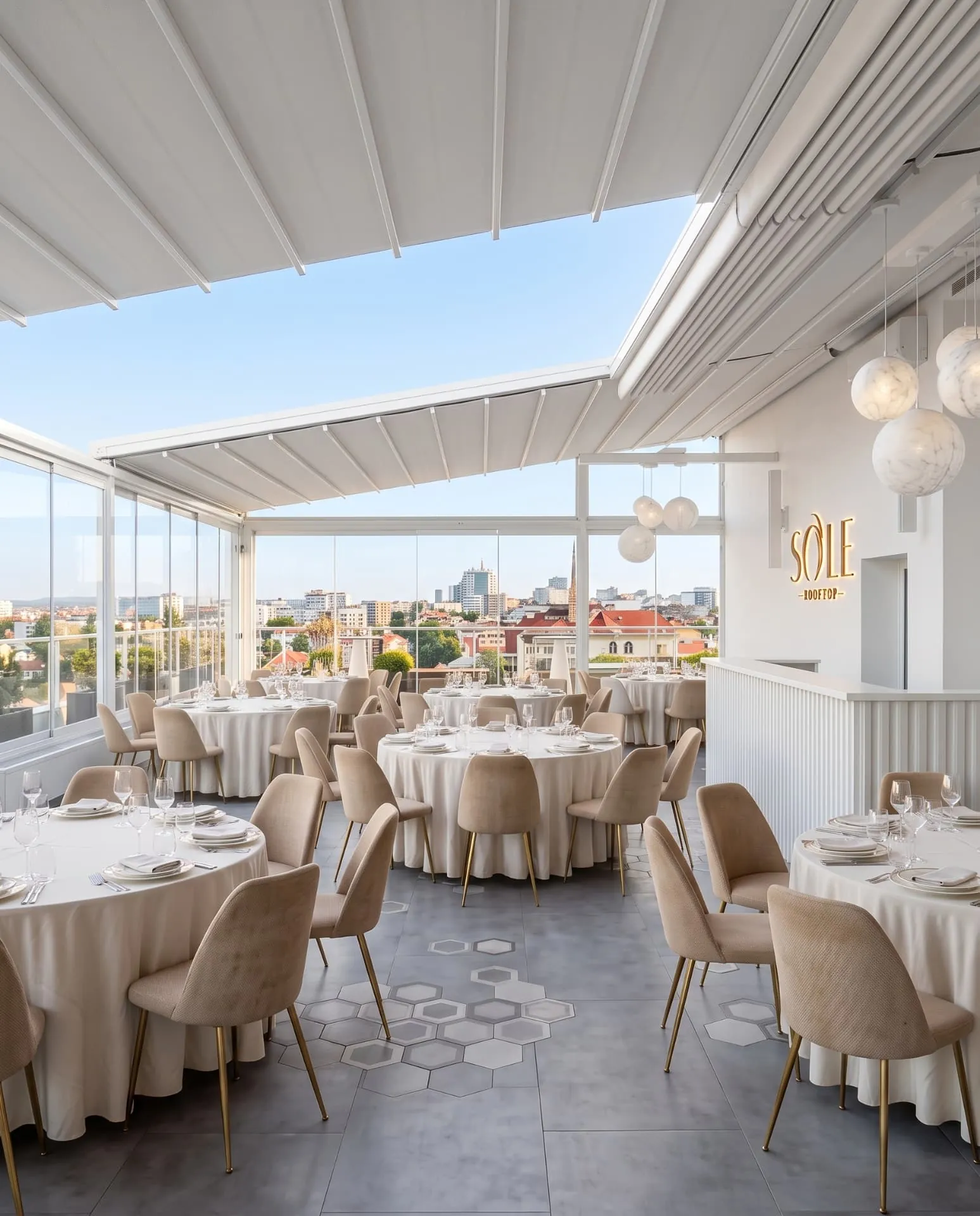 Sala Sole Rooftop ziua, luminată natural prin pereții de sticlă, cu mesele rotunde pregătite